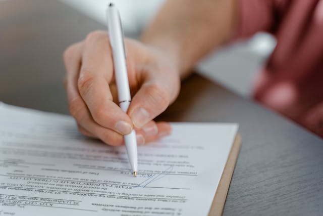 Person using a pen to sign a document